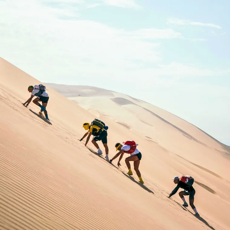 Runners climbing a sand dune